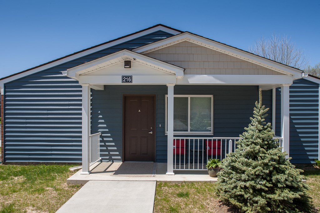 the front of a blue house with a porch and a door