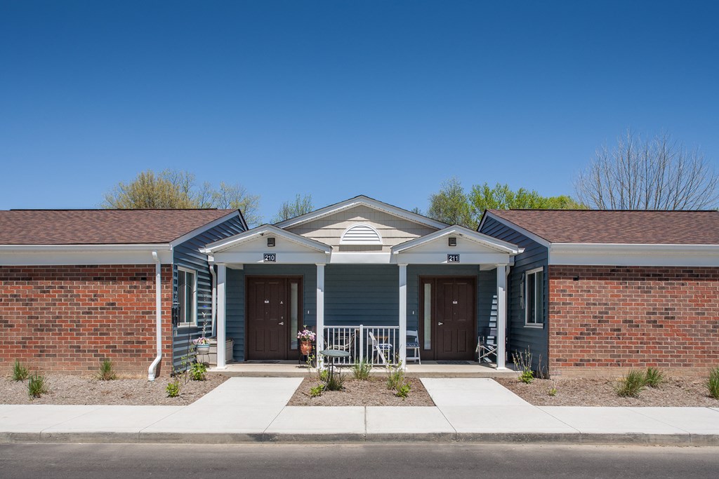 a blue house with a porch and a brick building