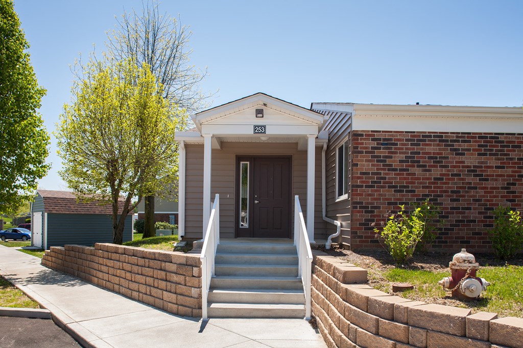the front of a brick house with stairs and a fire hydrant