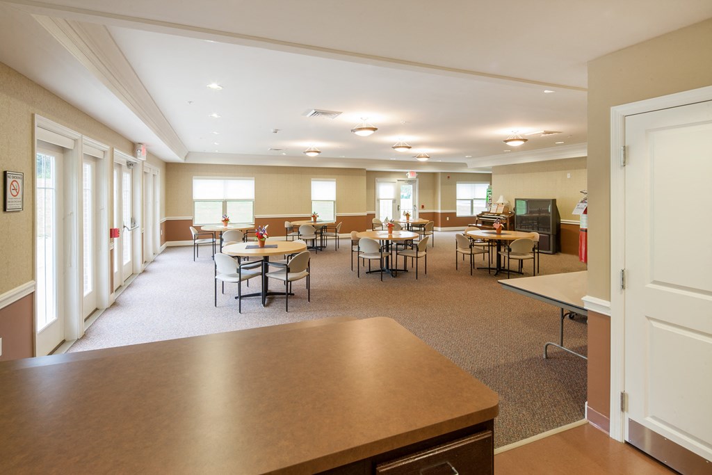 a dining room with tables and chairs and a kitchen in the center of the room