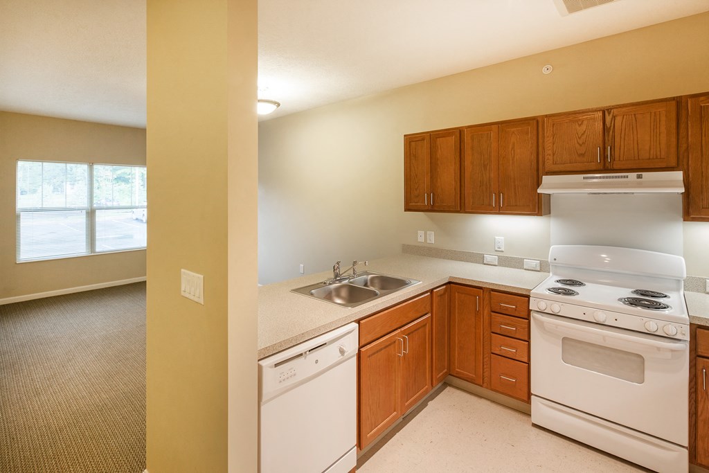 an empty kitchen with white appliances and wooden cabinets