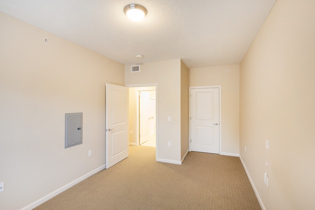 a spacious living room with white walls and a door opening to a hallway