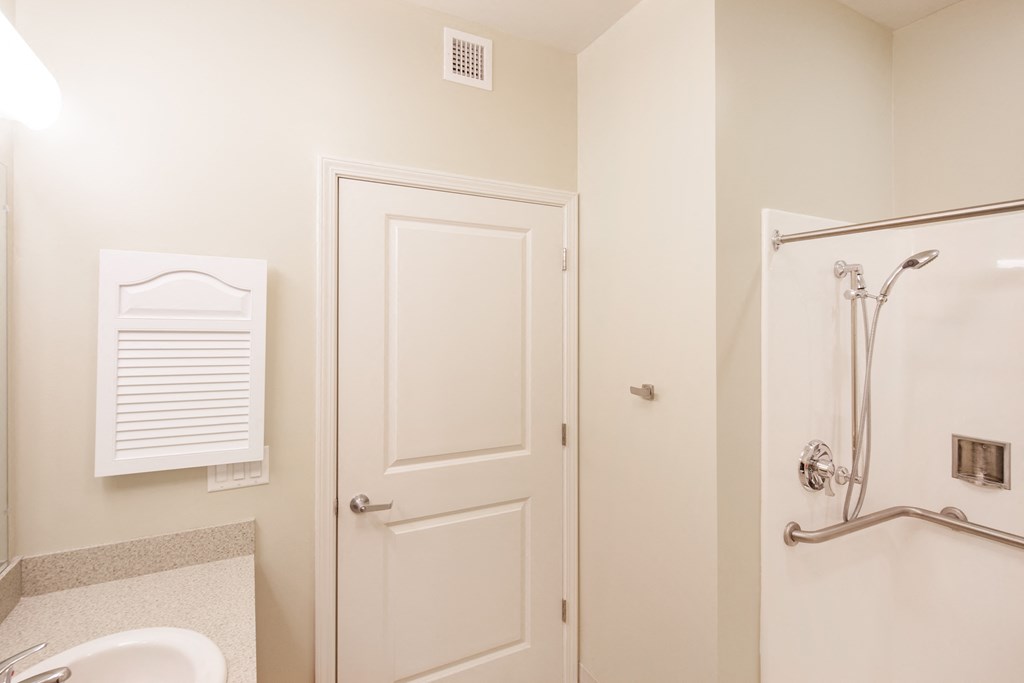 a bathroom with a sink and a shower and a white door