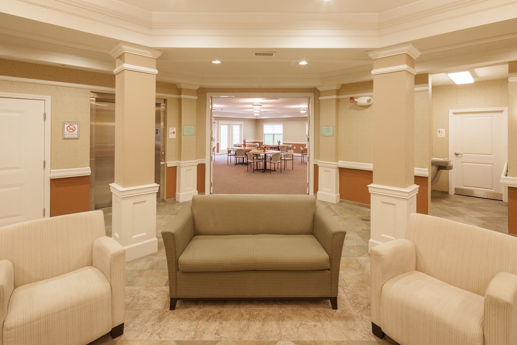 a living room with a couch and chairs and a dining room in the background