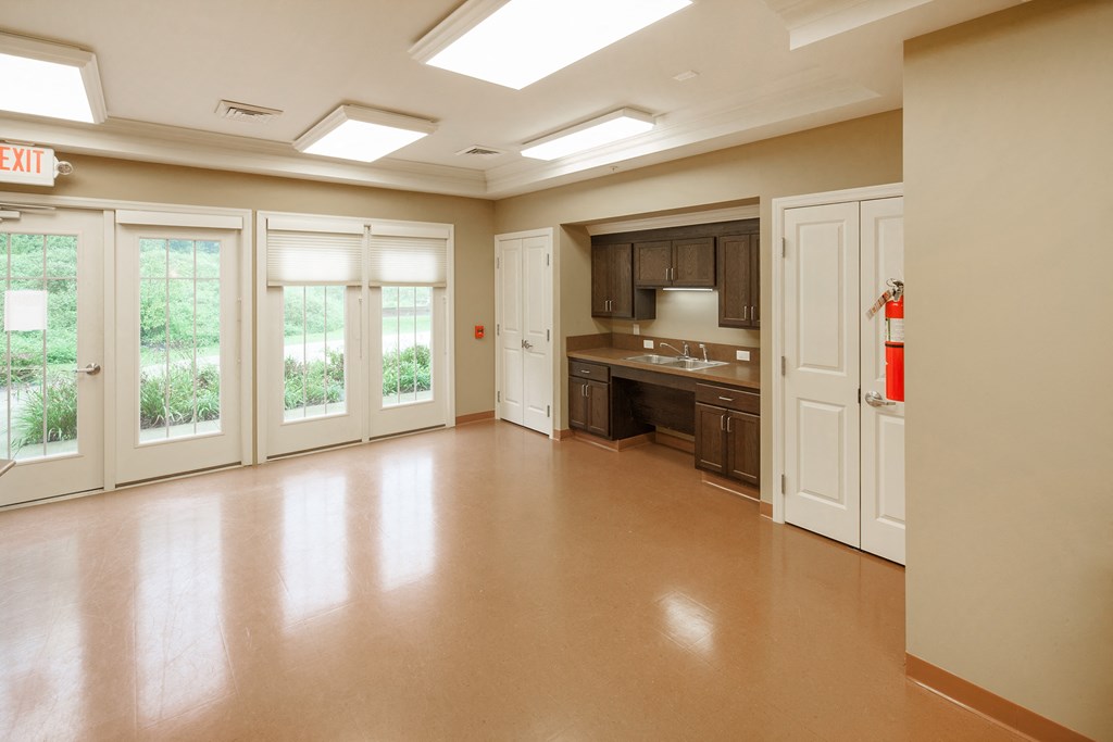an empty living room with a kitchen in the background