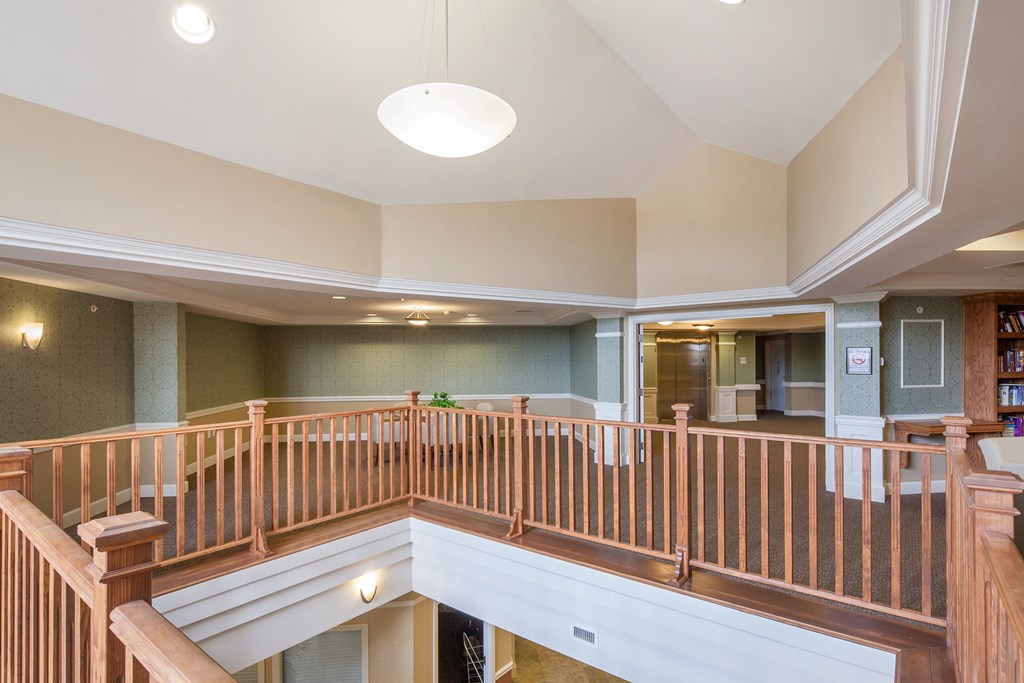 the upstairs lobby of a house with a landing with a wood railing and a staircase