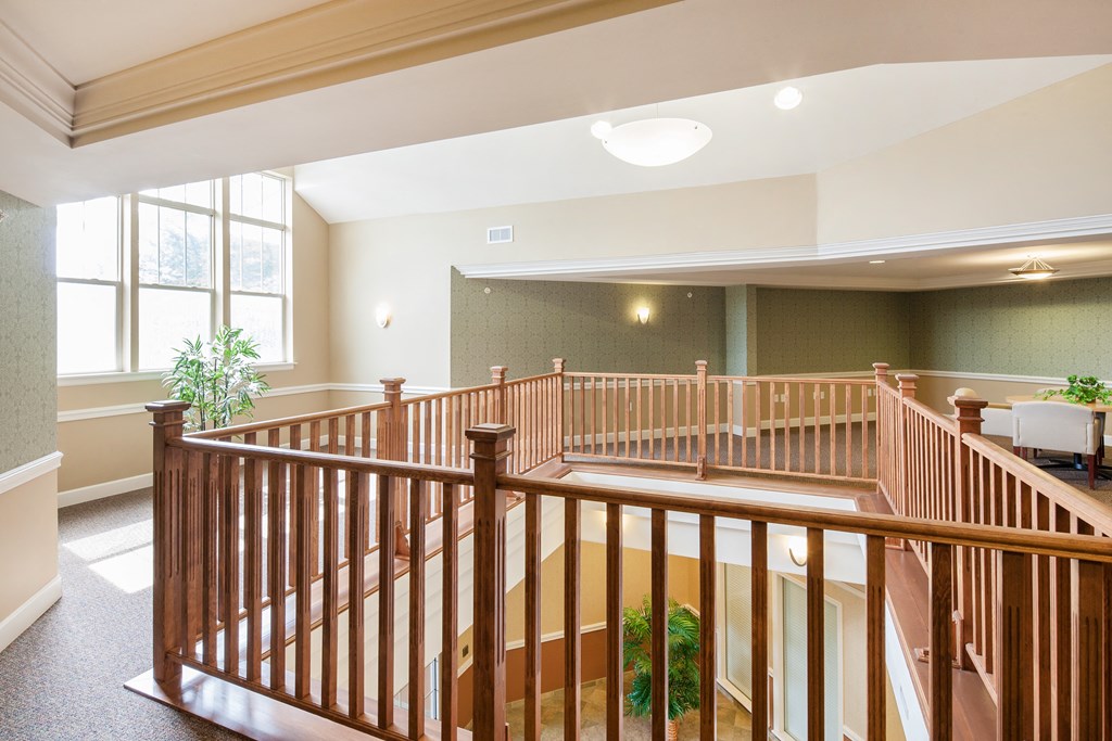 the upstairs lobby of a building with a staircase and a plant