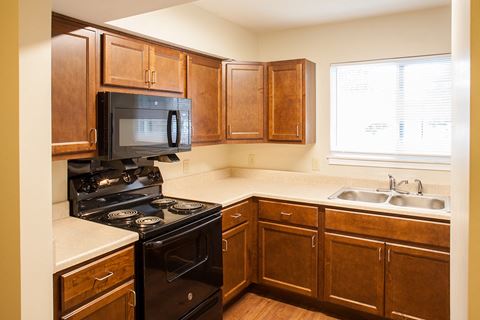a kitchen with wood cabinets and a black stove and a microwave