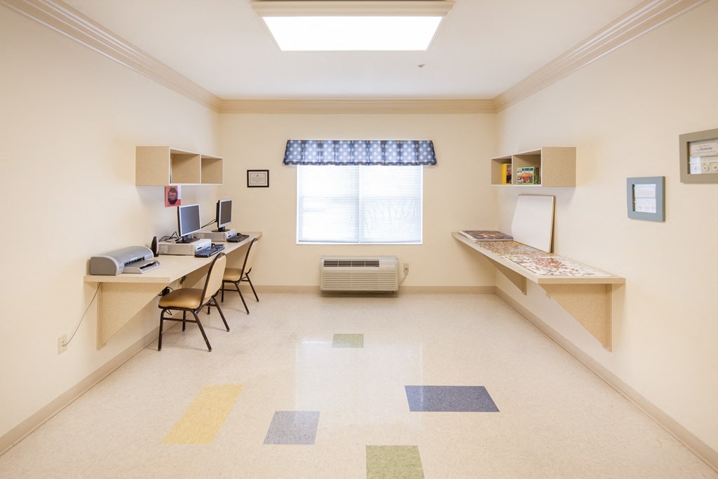 a study room with a desk and chairs and a window