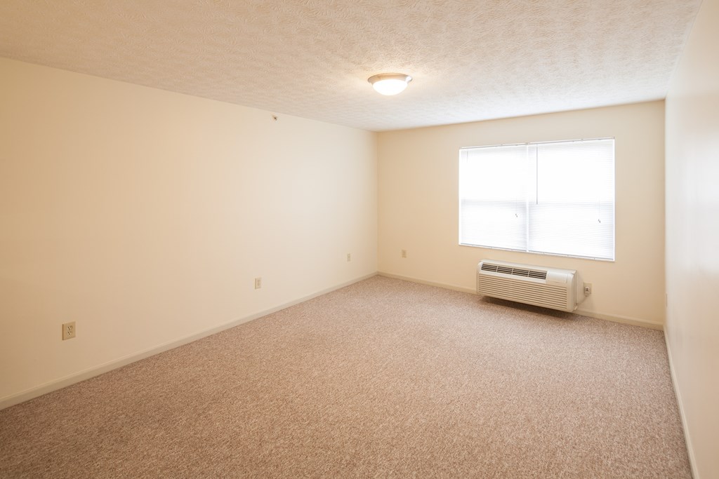 an empty room with a window and a heater
