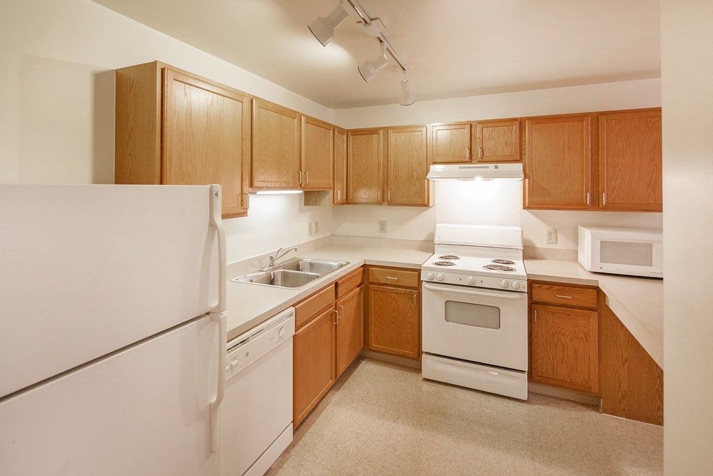 an empty kitchen with white appliances and wooden cabinets