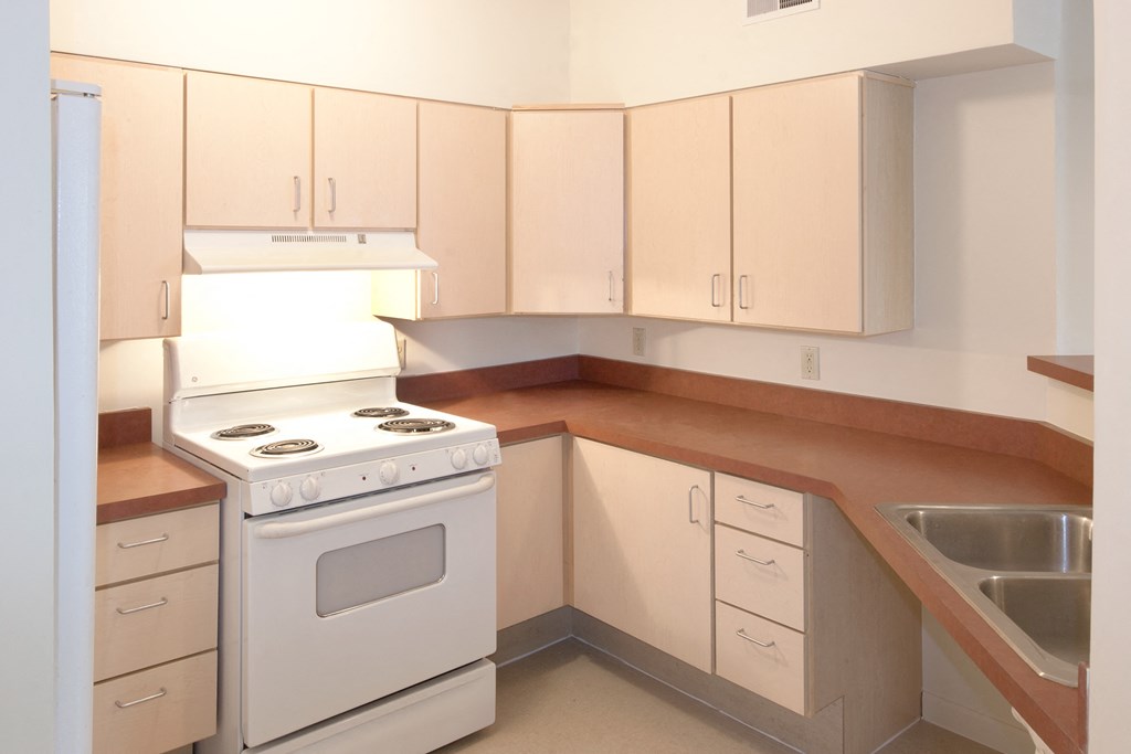 an empty kitchen with white appliances and wooden counters