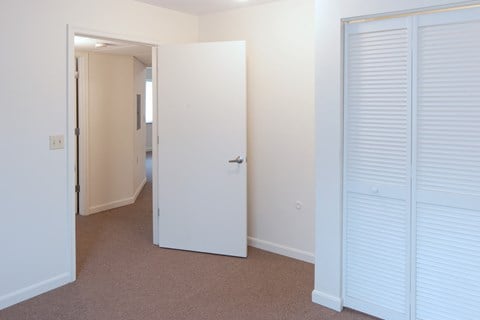 a bedroom with white closet doors and a door to a hallway