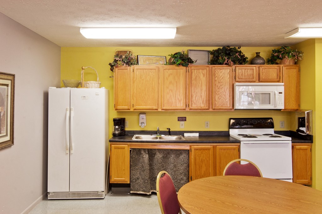 a kitchen with white appliances and wooden cabinets and a table