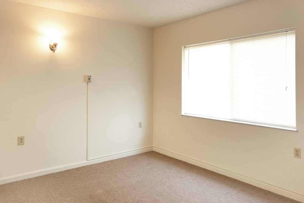 a bedroom with a large window and white walls