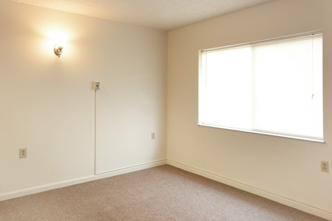 a bedroom with a large window and white walls