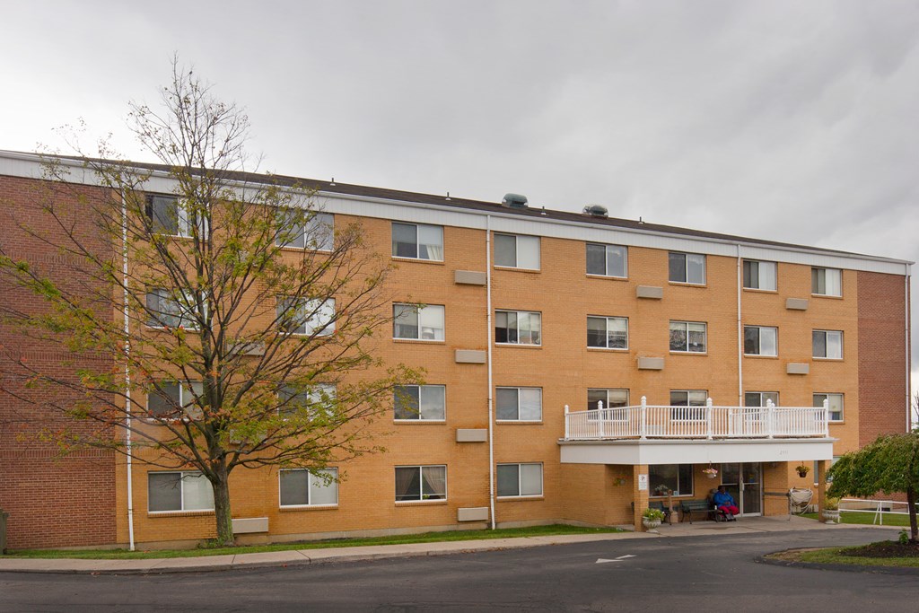 a brick apartment building with balconies and a tree