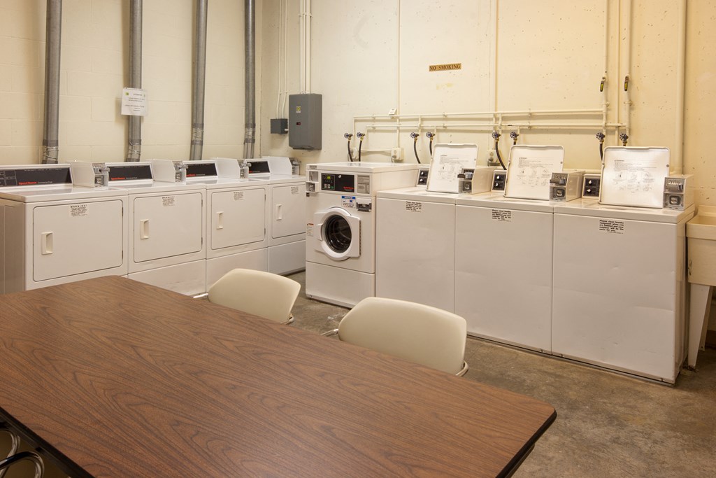 a group of washing machines in a room with a table and chairs