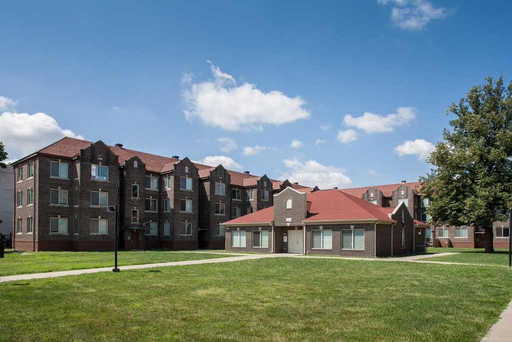 an apartment building with red roofs and a green lawn