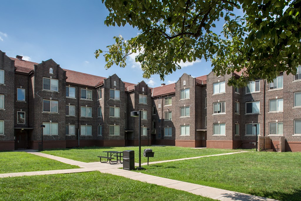 a brick building with a green lawn and a bench