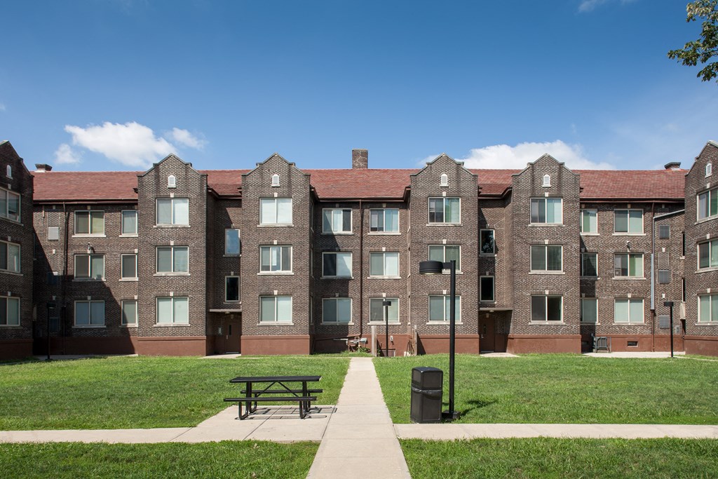 a large brick apartment building with a picnic table in the grass