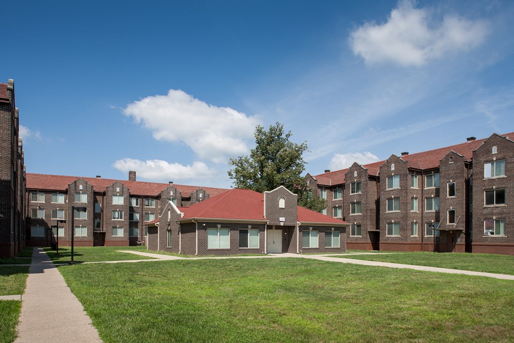 a row of brick apartment buildings on a green lawn