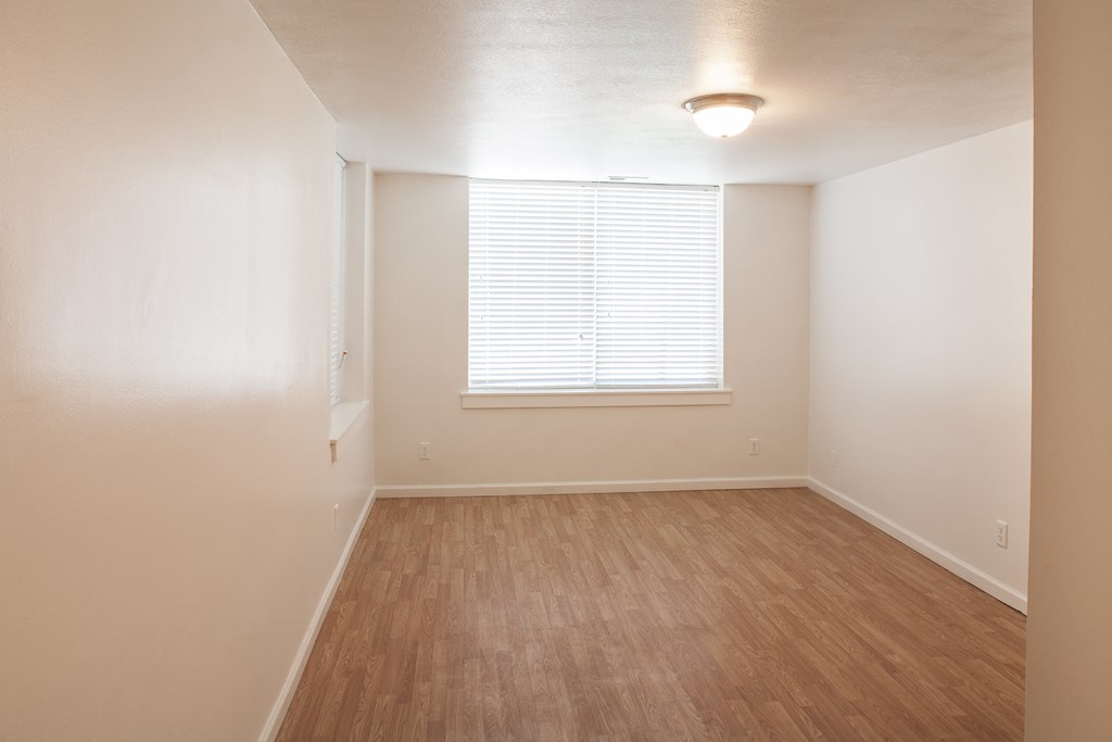 an empty living room with wood flooring and a window