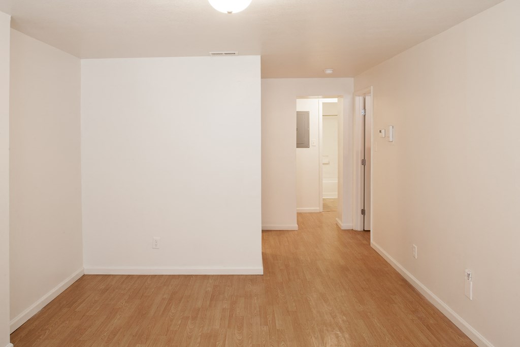 an empty room with a wood floor and white walls