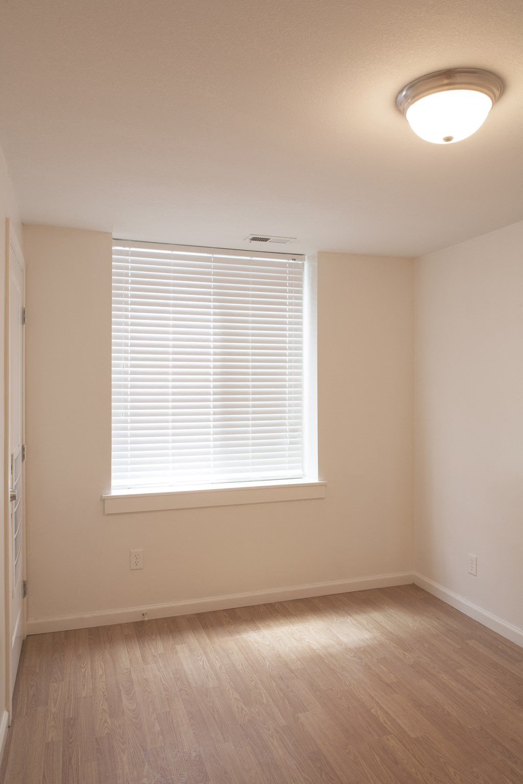 an empty living room with a large window and wooden floors