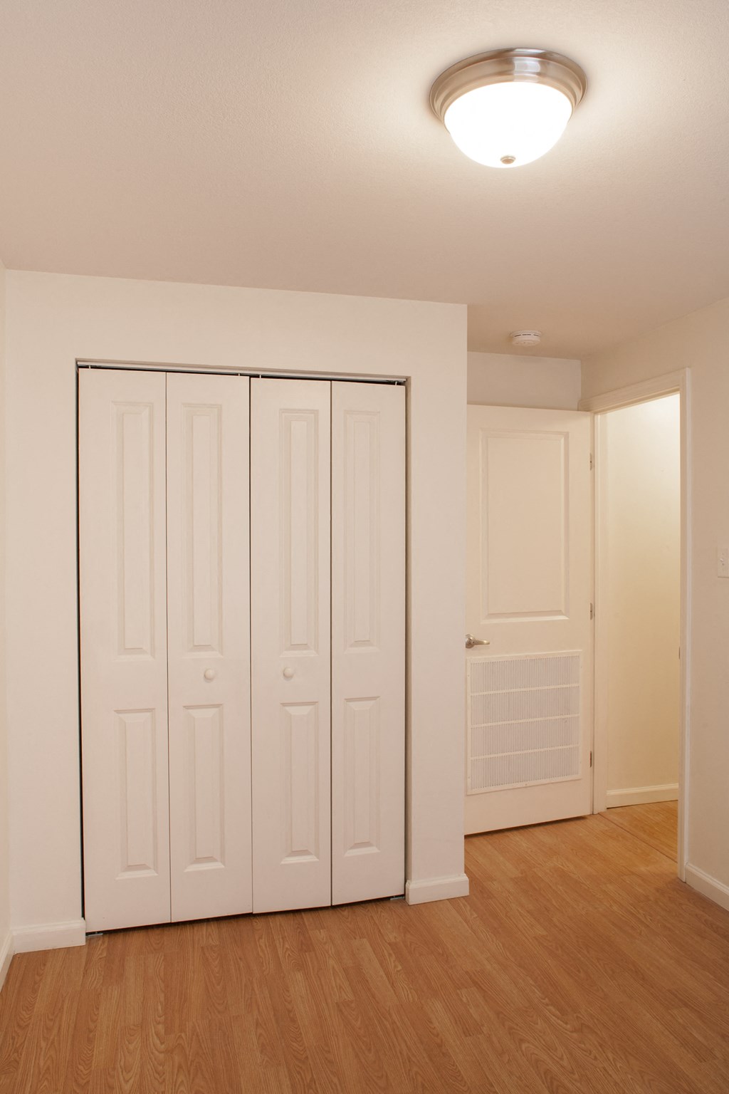 an empty living room with white closets and a wood floor