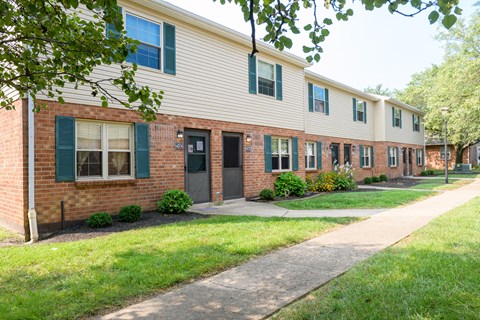 a brick apartment building with a sidewalk in front of it