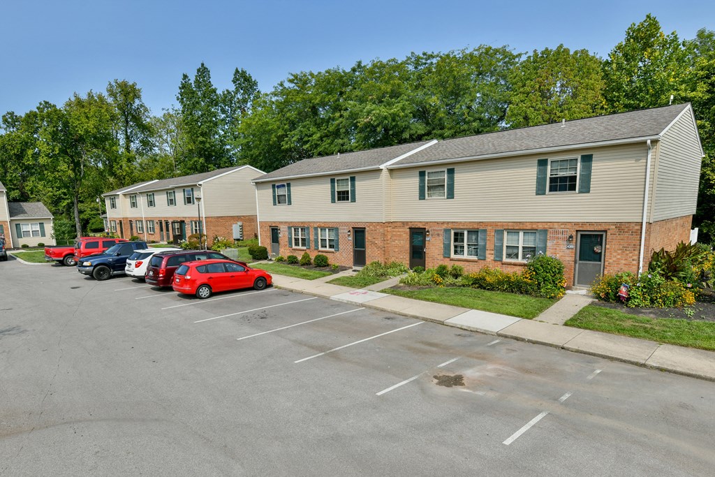 a parking lot in front of a apartment building with cars parked in front