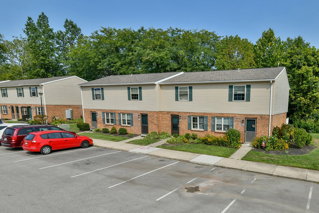 a parking lot in front of an apartment building with cars parked in front