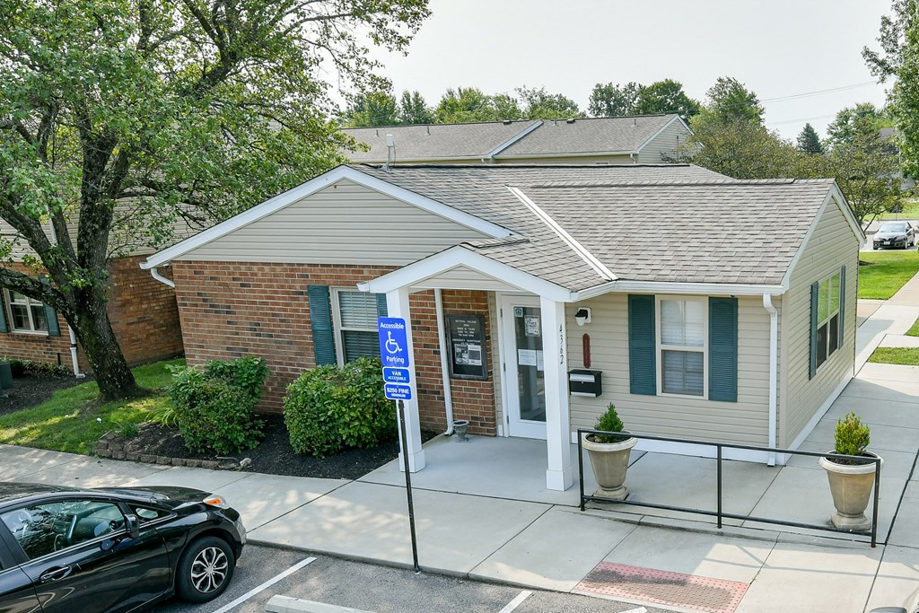 a small white house with a driveway and a parking lot