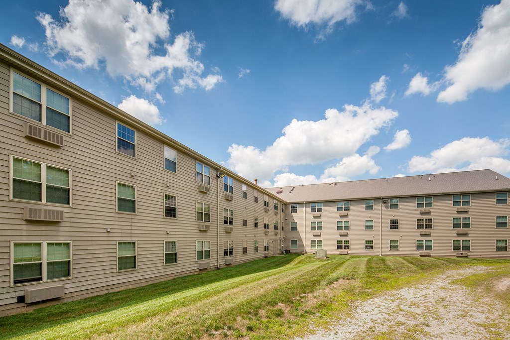 the exterior of an apartment building with green grass and a blue sky