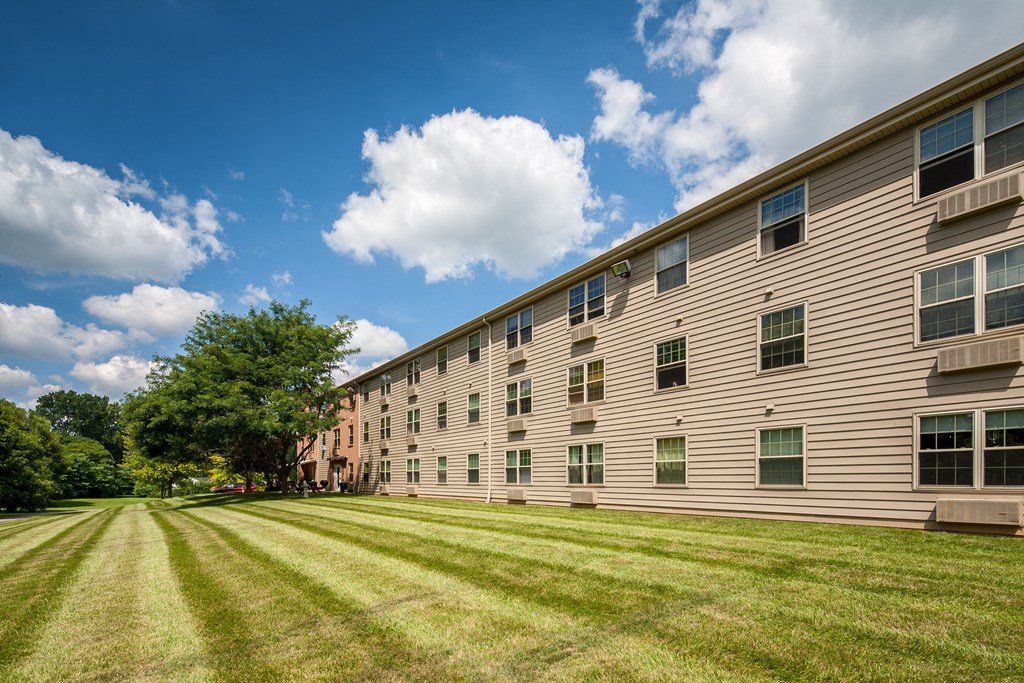 a large apartment building with a green lawn