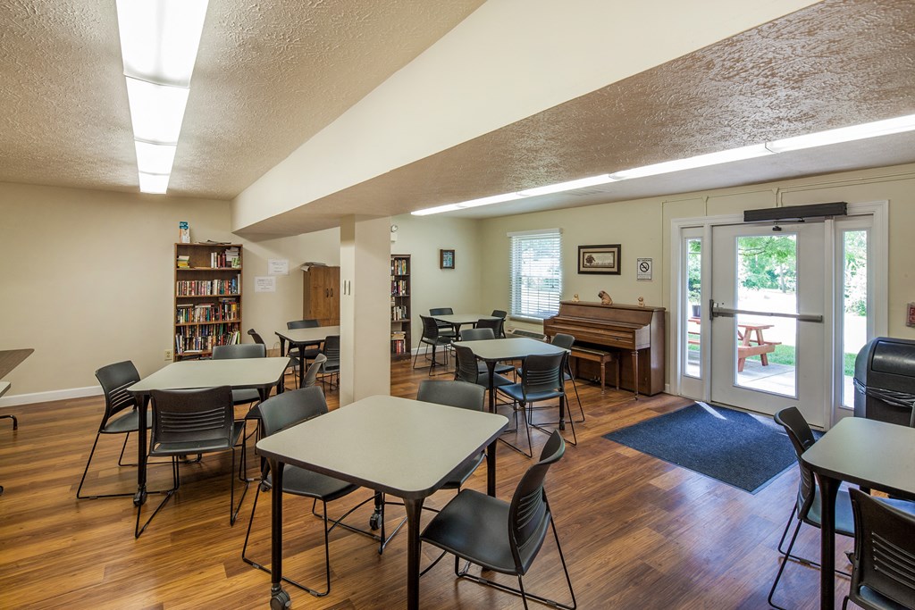 a community room with tables and chairs and a piano