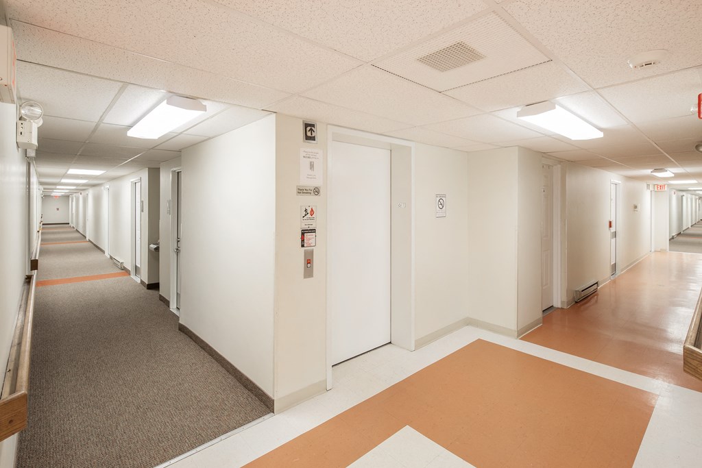 a hallway in a building with white walls and orange and white floors