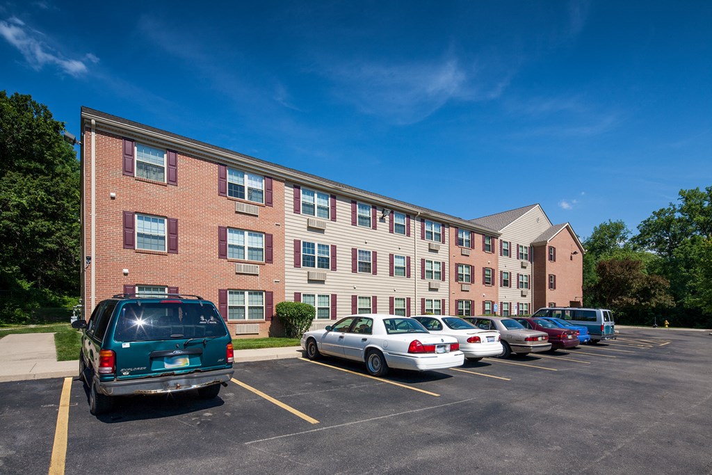 a large brick apartment building with cars parked in a parking lot