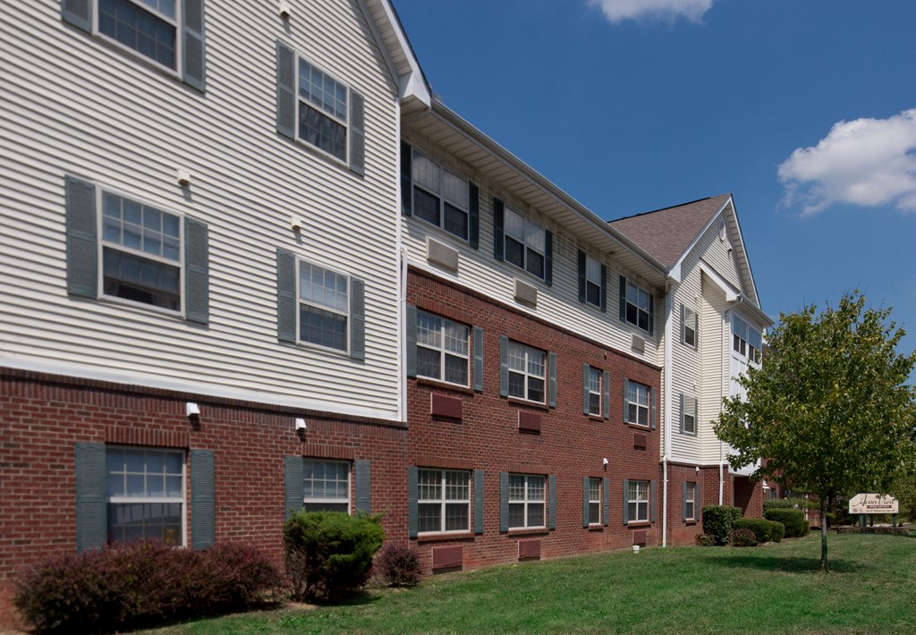 a brick apartment building with white siding and a green lawn