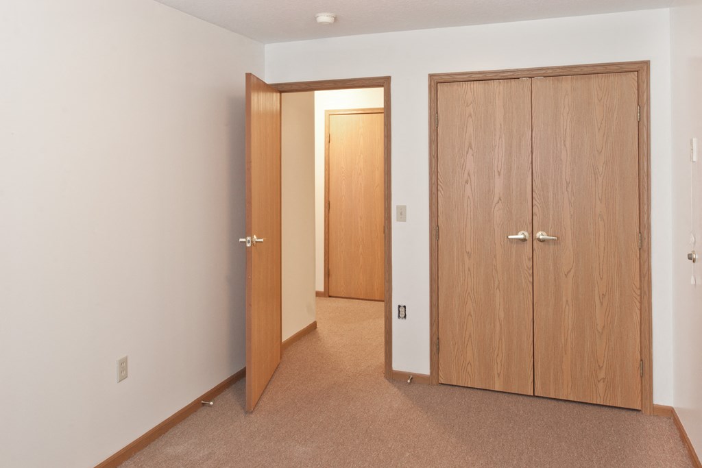 a bedroom with two doors and a door to a closet
