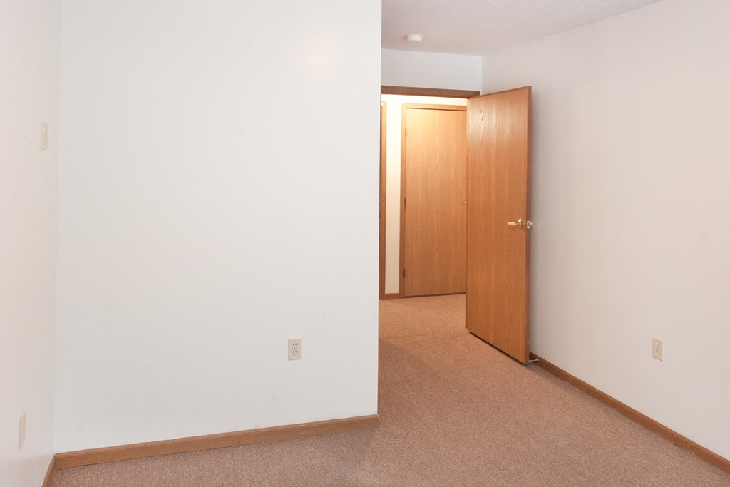 an empty room with white walls and a door to a closet