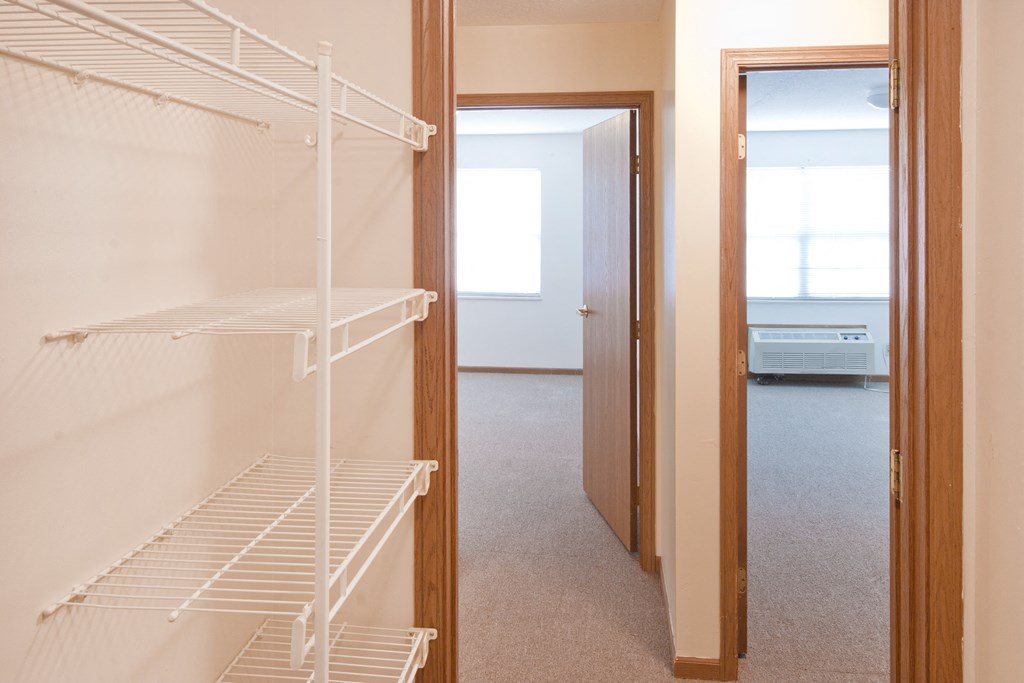 a bedroom with a closet with a white closet organizer and a door to a bathroom