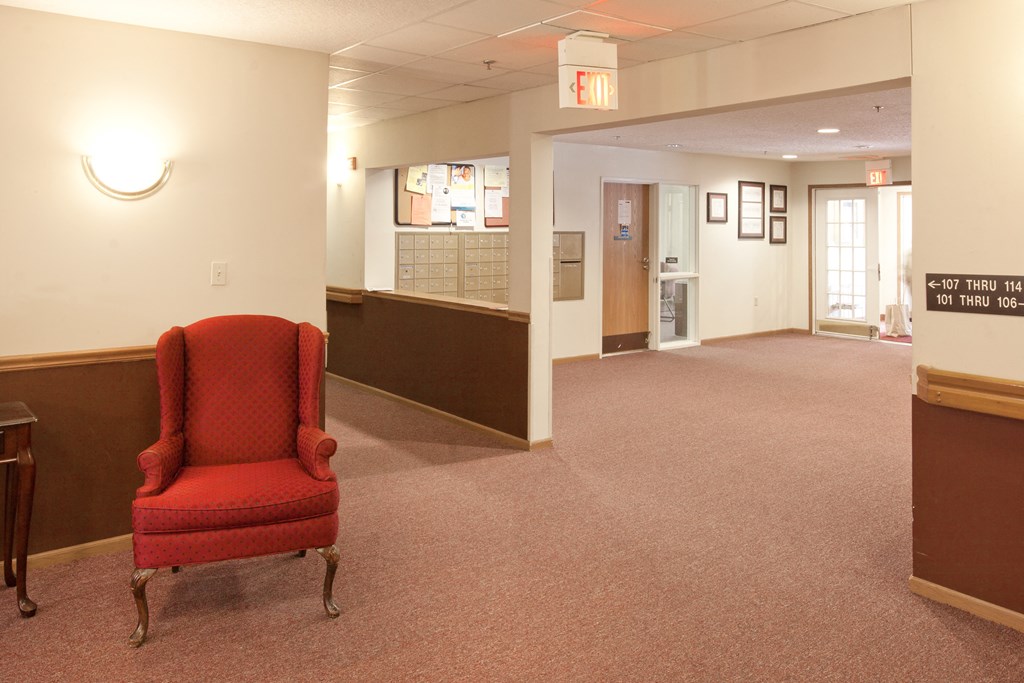 a red chair sits in the lobby of an empty hospital room