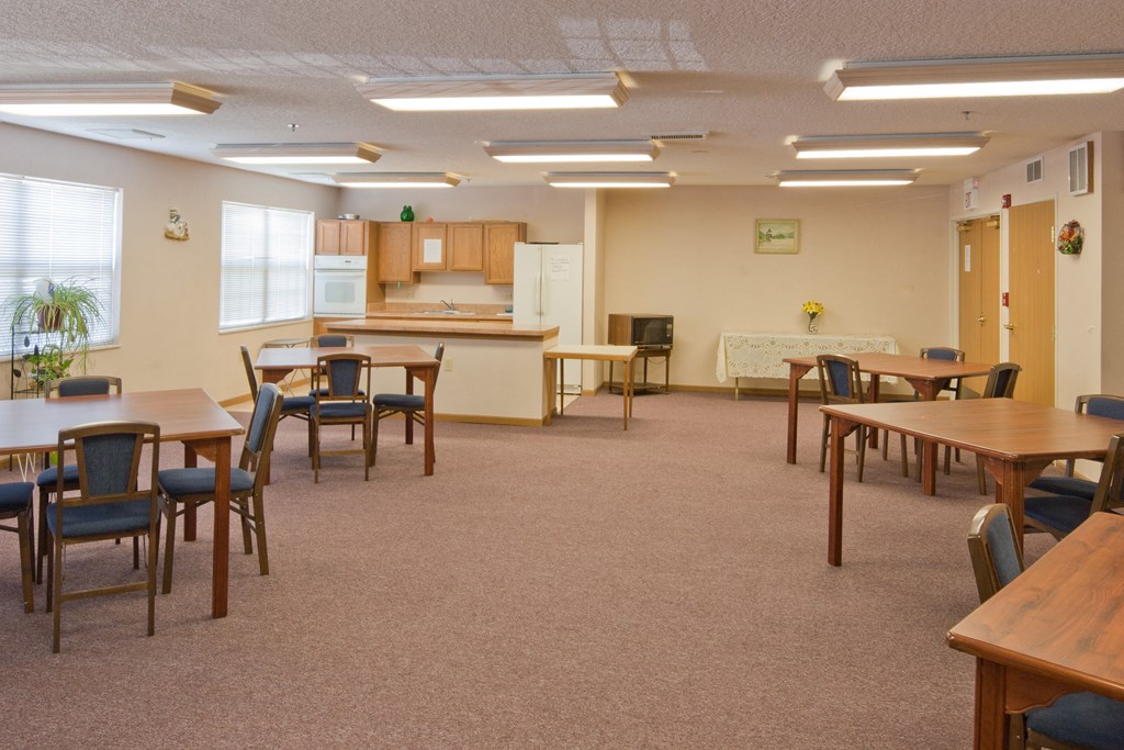 a multipurpose room with tables and chairs and a kitchen