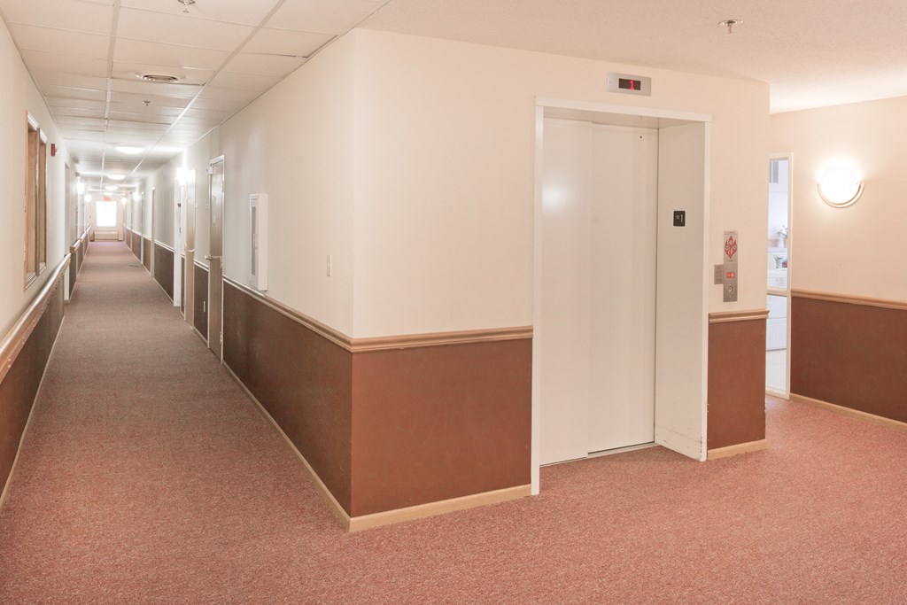 an empty hallway in a hospital with a pink carpet and white walls