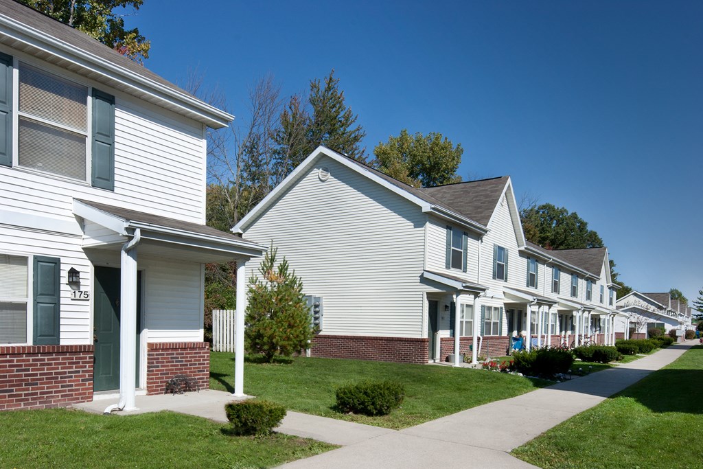 a row of houses with white siding and a sidewalk