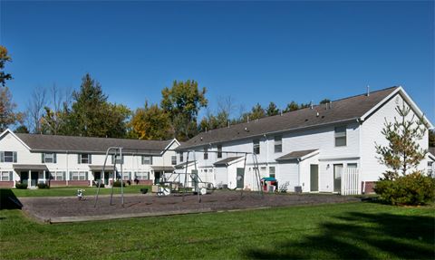 a group of white houses with a playground in the yard