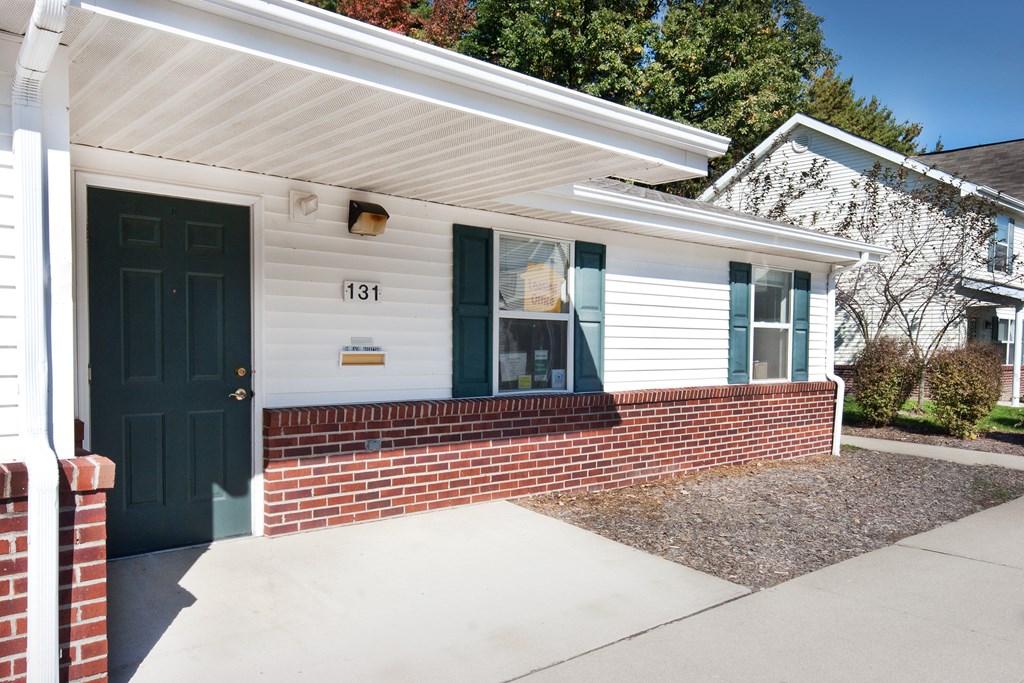 the front entrance of a white house with a blue door