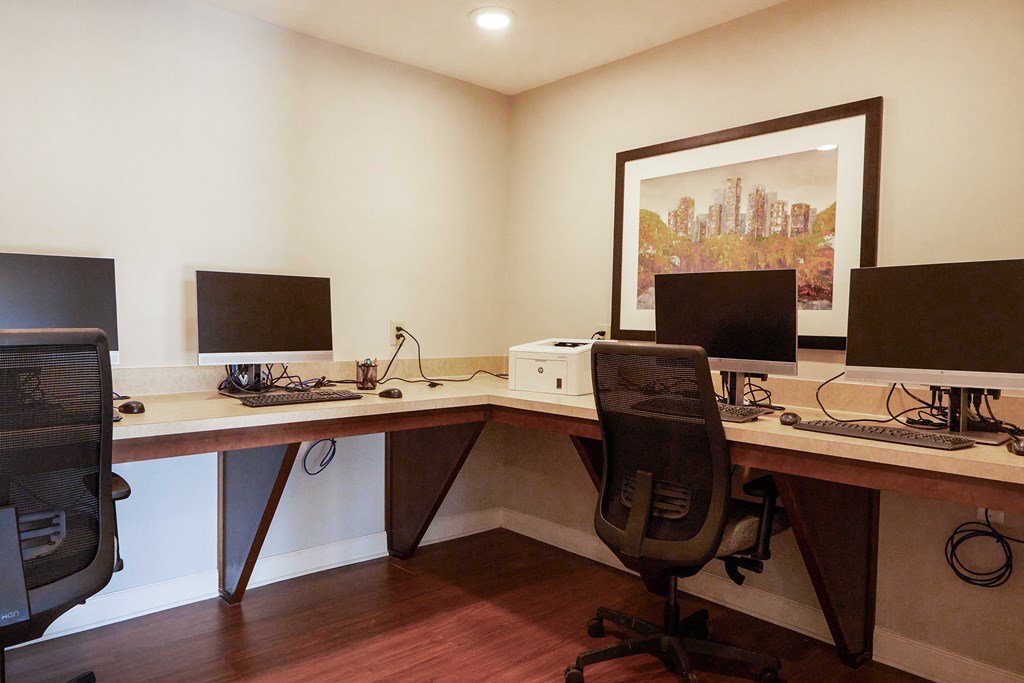 a home office with two computer desks and three monitors